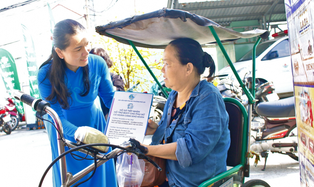 Bà Vi Thị Tâm Lai - Chủ tịch Hội LHPN phường Phú Lợi - trao thẻ bảo hiểm y tế cho bà Nguyễn Thị Minh Vân