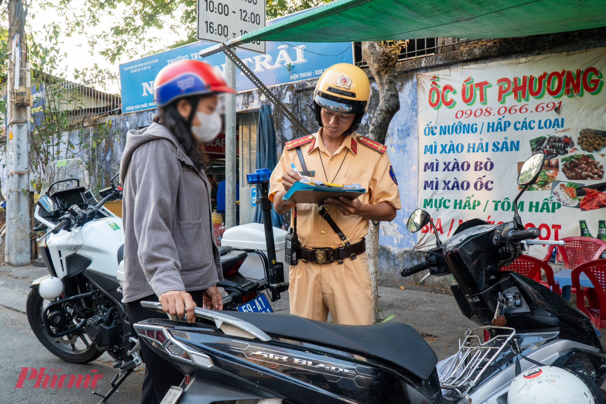Chị T bị CSGT  lập biên bản vì lỗi chở người ngồi sau không đội mũ bảo hiểm.