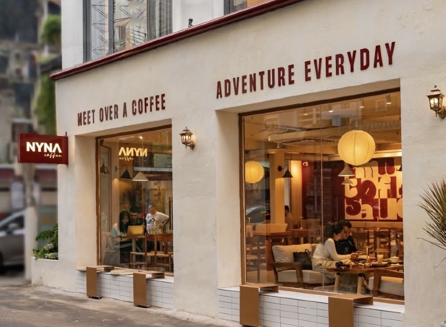 Nằm trên trục đường trung tâm Nguyễn Trãi (quận 1), Nyna Coffee là một trong số ít quán cà phê phục vụ xuyên đêm tại TP.HCM, thu hút đông đảo sinh viên và dân văn phòng làm việc khuya. Quán có mức giá dao động khoảng 30.000–70.000 đồng, được đánh giá là khá “dễ chịu” so với mặt bằng khu vực trung tâm. Không gian được thiết kế theo hướng hiện đại, bố trí nhiều khu vực ngồi linh hoạt, ánh sáng dịu và có đầy đủ ổ cắm điện, wifi ổn định, phù hợp cho việc học tập và làm việc dài giờ. Menu đa dạng từ cà phê truyền thống, cà phê máy đến trà trái cây và nước ép, hương vị ở mức ổn định, dễ uống. Về đêm, quán trở nên yên tĩnh hơn, trở thành điểm đến quen thuộc của những “cú đêm” cần một nơi vừa làm việc vừa thư giãn giữa lòng thành phố.