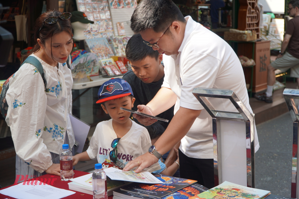 Phụ huynh và các em nhỏ trải nghiệm bộ sách tương tác AR tại sự kiện.