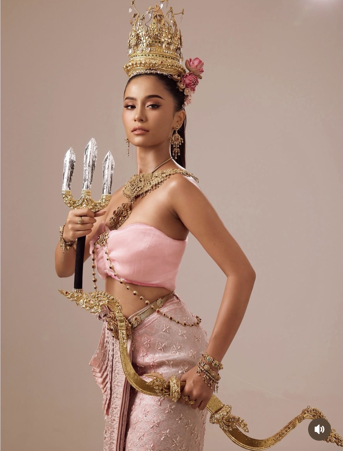 Hoà nhịp cùng không khí Songkran, Songkran, Á hậu Hoà bình Thái Lan Malaika Khan khoe hình ảnh mới với thần thái mạnh mẽ pha lẫn nét quyến rũ đặc trưng của mỹ nhân Thái Lan. Cô diện trang phục truyền thống cách tân với tông hồng phấn chủ đạo, gồm áo quây ôm sát và chân váy lụa thêu hoa tinh xảo, tôn lên vóc dáng săn chắc cùng vòng eo thon gọn. Điểm nhấn nằm ở hệ thống phụ kiện dát vàng cầu kỳ, từ vương miện cao mang phong cách hoàng gia, vòng cổ bản lớn đến thắt lưng và trang sức đính đá tạo nên tổng thể lộng lẫy, quyền lực.