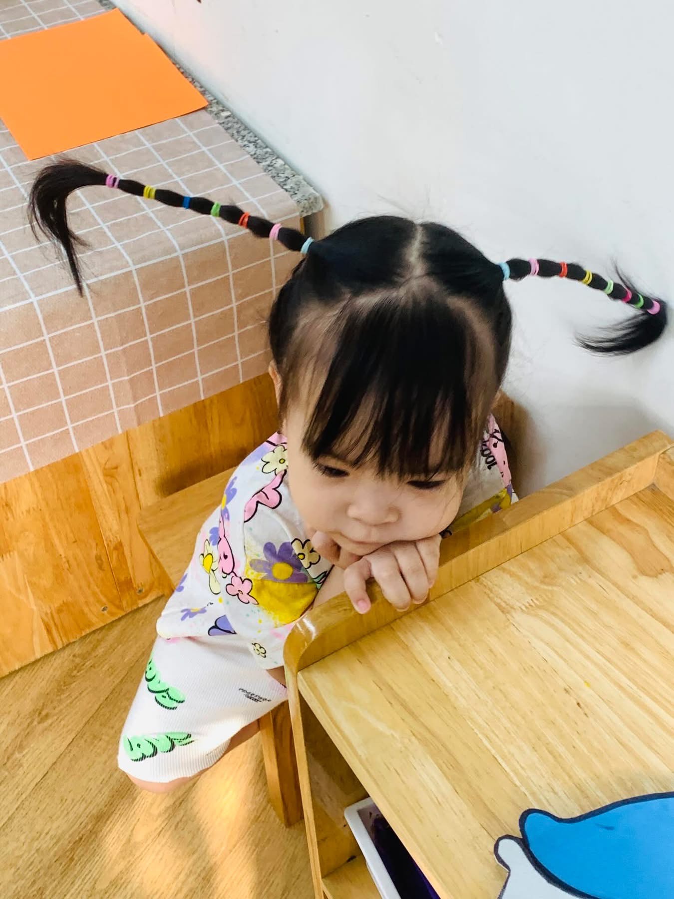 Kiểu tóc này nhìn qua cứ tưởng 'ăng-ten bắt sóng Wi-Fi phiên bản nhí'. Hai bên được tết gọn gàng rồi kéo thẳng ra như 2 cánh quạt, điểm xuyết bằng hàng loạt dây thun đủ màu sắc, trông như cầu vồng mini đang đu đưa. Để làm kiểu tóc này, các mẹ hãy chia tóc bé làm 2 bên đều nhau, buộc cao lên thành 2 chùm. Sau đó tết từng bên thành bím dài, cứ mỗi đoạn lại cột một sợi chun nhỏ đủ màu cho thêm phần sinh động. Cuối cùng kéo nhẹ 2 bím tóc sang ngang cho xòe ra như cánh, chỉnh lại cho cân đối là xong. Thành quả là một kiểu tóc vừa đáng yêu vừa hài hước, đảm bảo ai nhìn cũng phải bật cười vì trông bé như đang chuẩn bị… cất cánh.