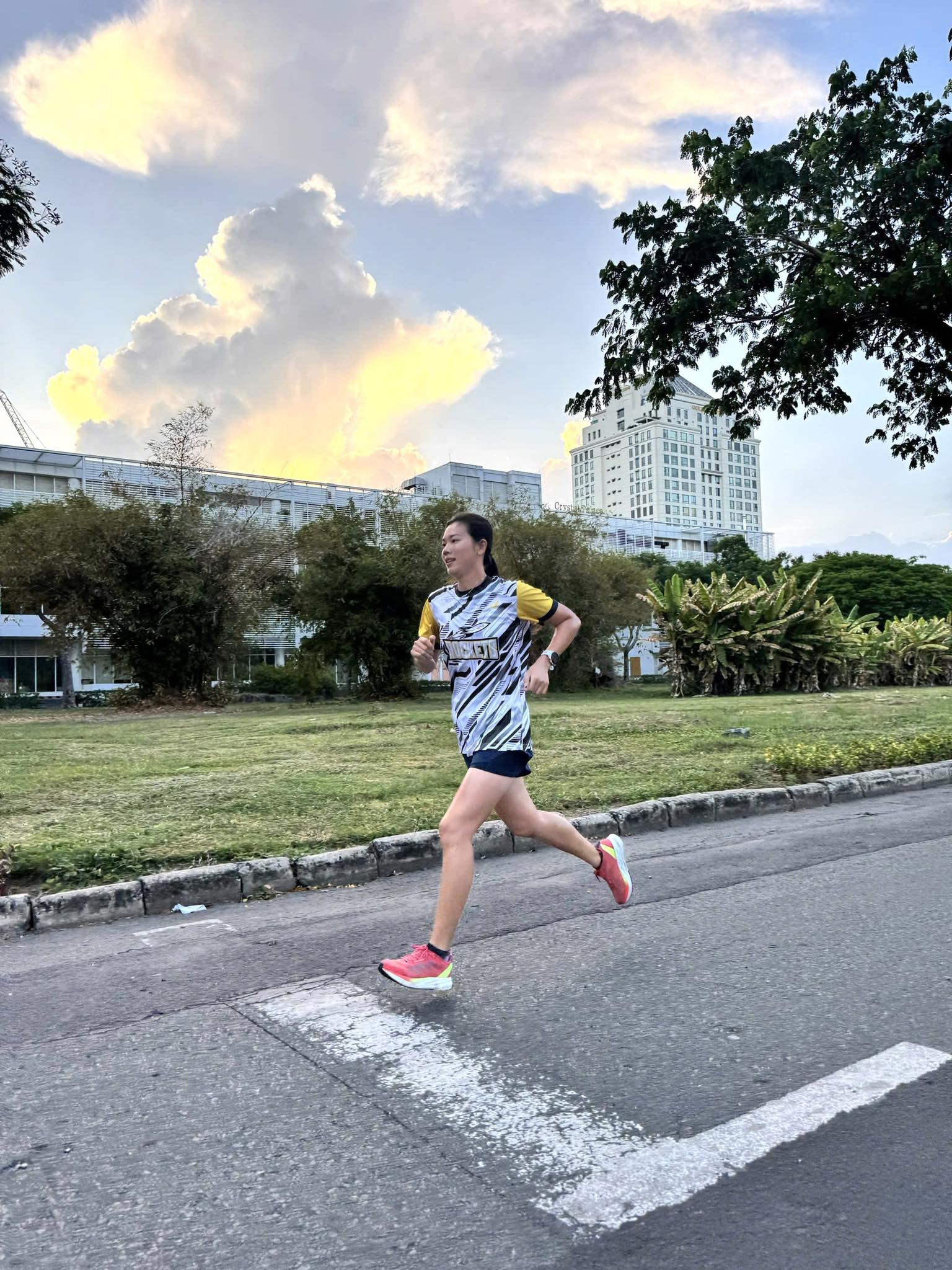 Nữ vận động viên toát lên vẻ ngoài năng động, trẻ trung và tràn đầy năng lượng khi tập luyện chạy bộ hàng ngày. Mặc dù chỉ là một giải chạy thường ngày, Ánh Viên vẫn ưu tiên sự thoải mái và linh hoạt với bộ áo thun thể thao xanh đen phối họa tiết sọc vằn và tay áo màu vàng nổi bật. Chất liệu vải chuyên dụng có khả năng thoát mồ hôi nhanh, giúp cô duy trì thân nhiệt ổn định trong suốt hành trình dài.