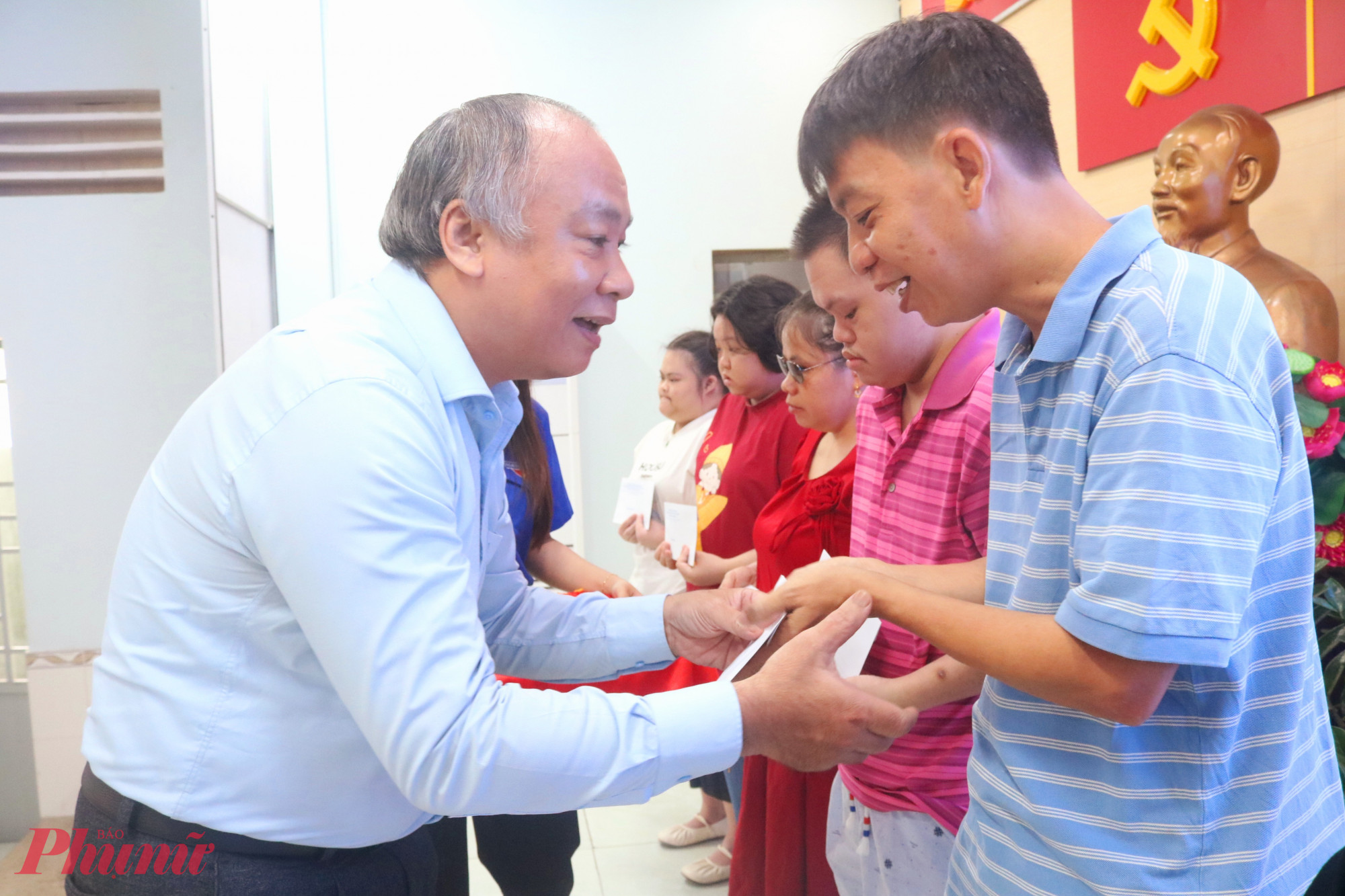 Ông Lê Văn Cường – Phó bí thư thường trực Đảng ủy Phường Trung Mỹ Tây – trao quà và trò chuyện động viên anh chị em khuyết tật có hoàn cảnh khó khăn - Ảnh: Mẫn Nhi