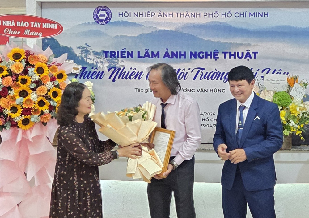 Lãnh đạo Hội Nhiếp ảnh TPHCM tặng hoa và trao giấy chứng nhận bảo trợ triển lãm cho NSNA Trương Văn Hùng - Ảnh: Ngọc Tuyết