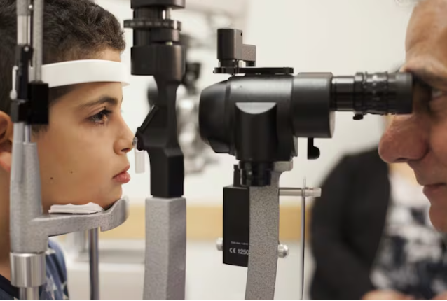 , Albert Maguire (bên phải) đang kiểm tra mắt cho Misa Kaabali, 8 tuổi, tại Bệnh viện Nhi đồng Philadelphia. Misa được điều trị bằng liệu pháp gen khi mới 4 tuổi. Bill West