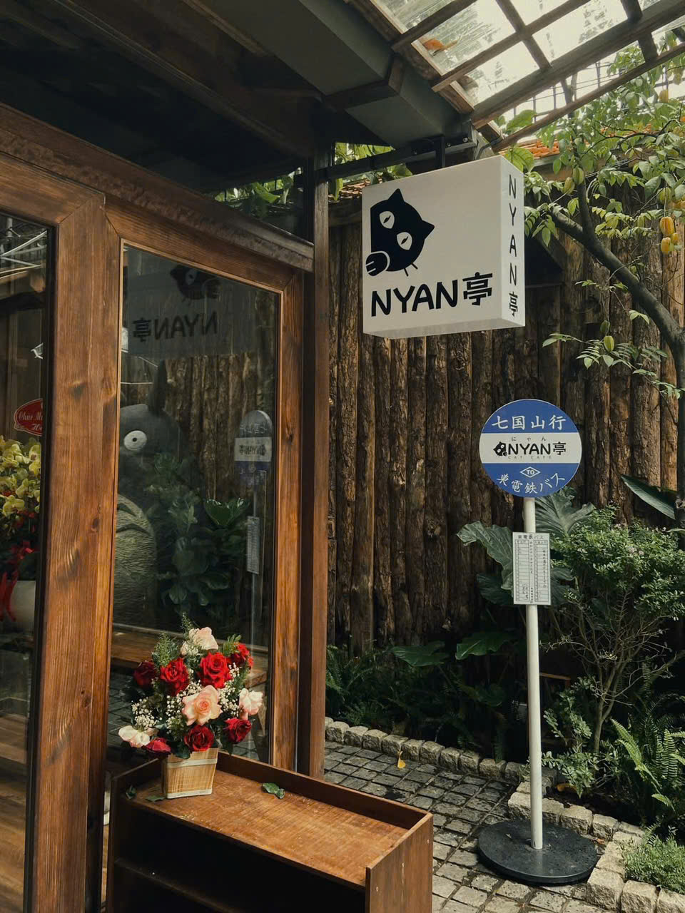 Nyan Tei Cafe (4 Lê Đình Thám, phường Tân Sơn Nhì) gây ấn tượng ngay từ cái nhìn đầu tiên với không gian đậm chất Nhật Bản pha chút dễ thương đặc trưng văn hóa pop. Bao quanh quán là những mảng xanh nhẹ nhàng, kết hợp cùng kiến trúc gỗ và các chi tiết trang trí như đèn lồng, rèm noren hay cửa trượt, tái hiện hình ảnh một góc phố nhỏ ở Tokyo. Sự hòa quyện giữa thiên nhiên và kiến trúc khiến nơi đây vừa mang nét cổ kính, vừa giữ được sự tươi mới, rất phù hợp với xu hướng check-in hiện nay.