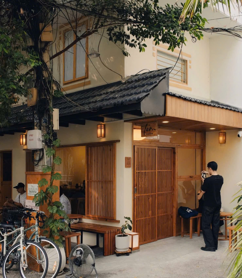 Ten Coffee (214/19/56 Nguyễn Văn Nguyễn, phường Tân Định) là một trong những quán cà phê mang phong cách Nhật Bản tối giản rõ nét, với thiết kế thiên về sự tinh gọn và cân bằng. Không gian sử dụng gam màu trung tính, kết hợp cùng chất liệu gỗ và ánh sáng tự nhiên để tạo nên cảm giác ấm áp nhưng không nặng nề. Những khoảng trống được giữ lại có chủ ý, giúp quán mang đậm tinh thần “less is more” trong kiến trúc Nhật.