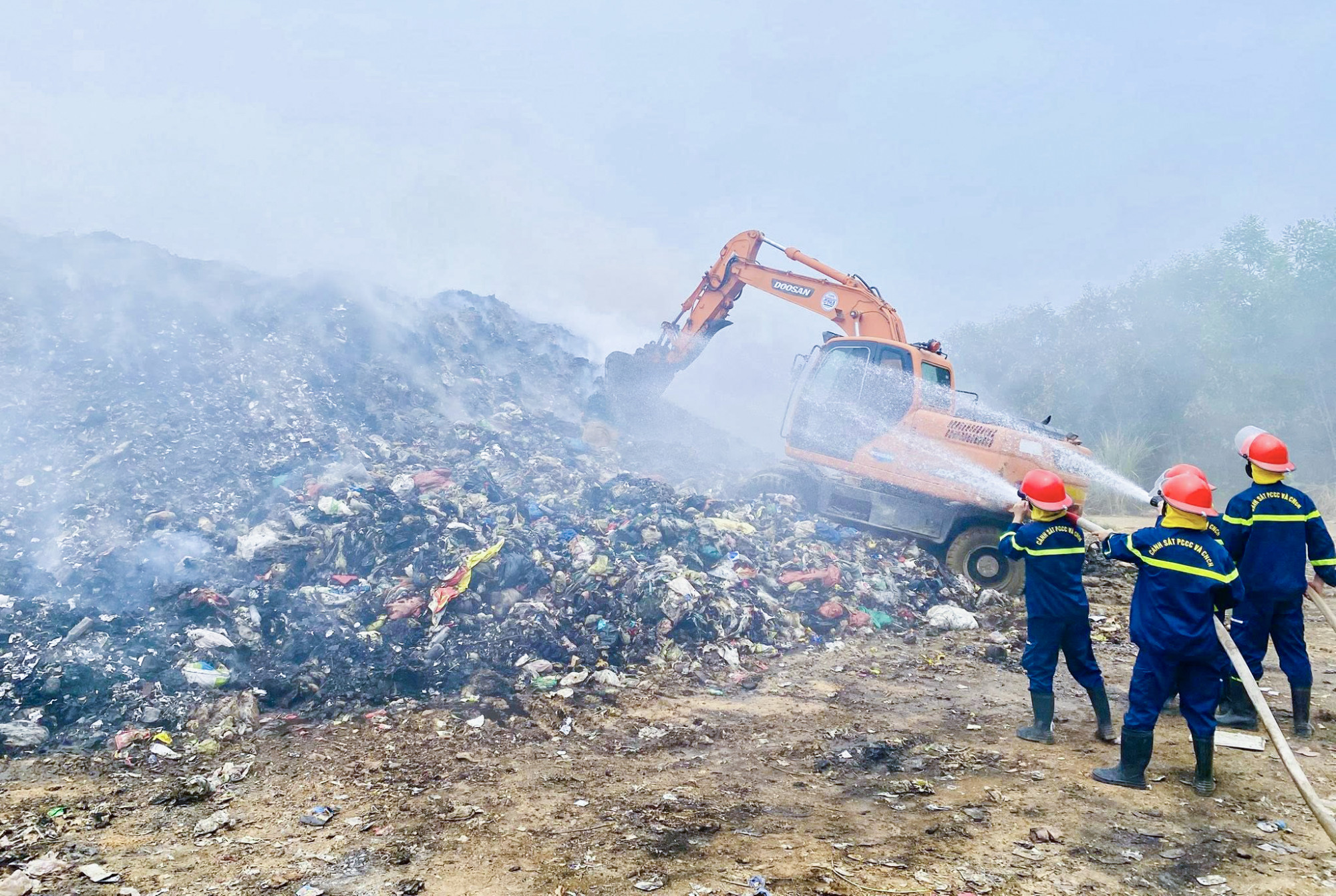 Lực lượng chức năng nỗ lực dập lửa âm ỉ bên trong bãi rác - Ảnh: Khánh Trung