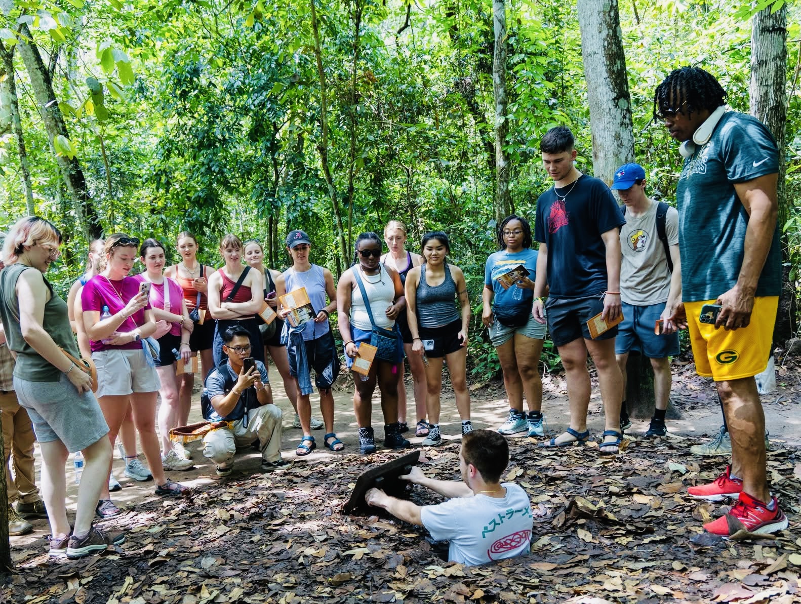 Khách quốc tế thích thú trải nghiệm địa đạo Củ Chi, thưởng thức khoai mì chấm muối mè. Ảnh: Q.T