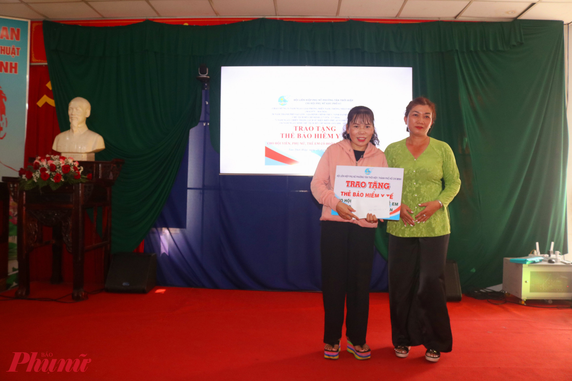 Chị Đỗ Thị Tâm Tuyền – Chi hội trưởng Chi hội Phụ nữ khu phố 67 (bìa phải) – trao bảng tượng trưng việc tặng thẻ bảo hiểm y tế cho chị Hoàng Thị Thủy - Ảnh: Thảo Nguyên