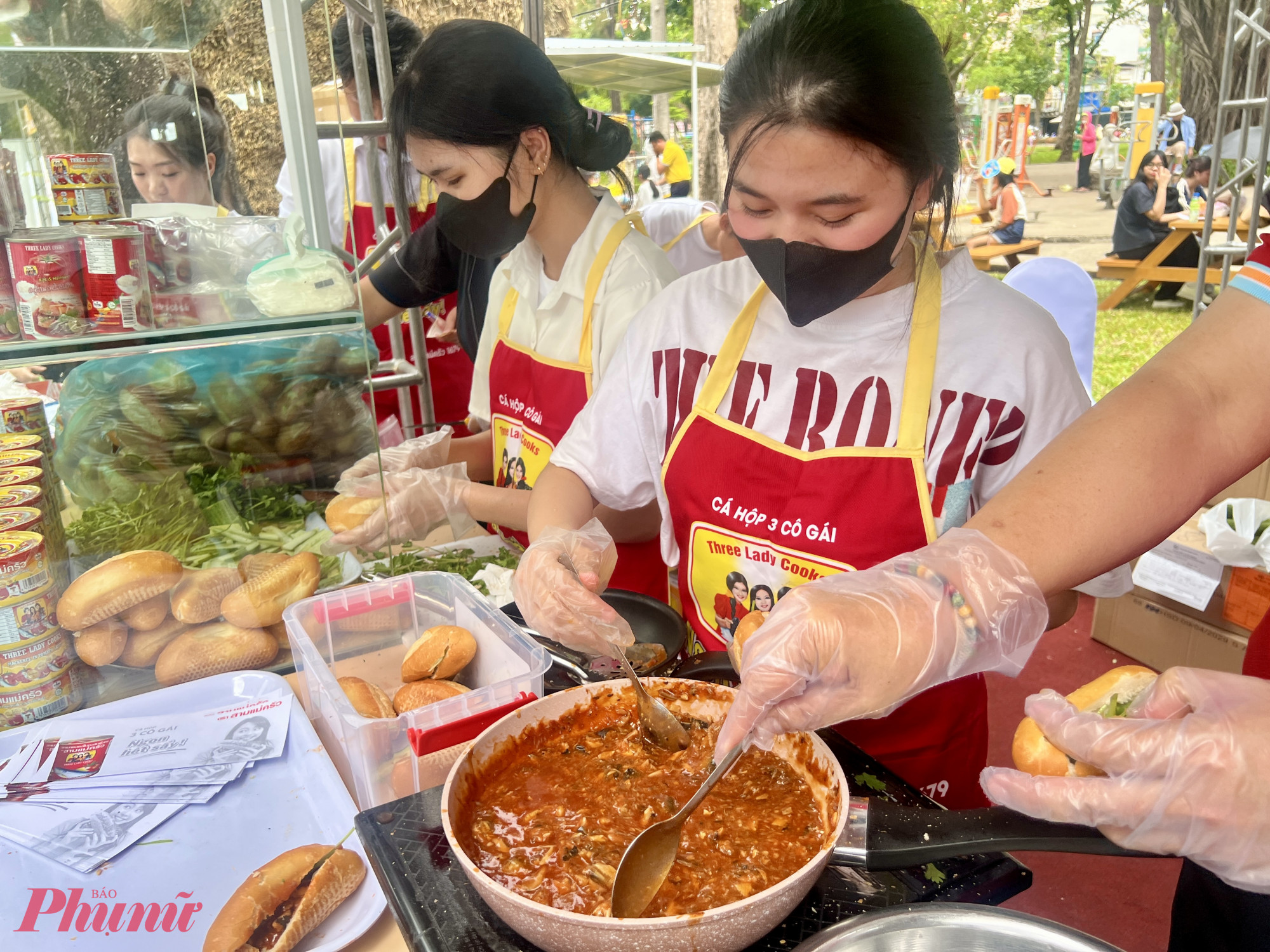 Gian hàng bánh mì cá hộp 2 cô gái chế biến nguyên liệu tại chỗ phục vụ hàng dài khách chờ thưởng thức bánh mì tại Lễ hội Bánh mì Việt Nam lần thứ 4, năm 2026. Ảnh: Quốc Thái