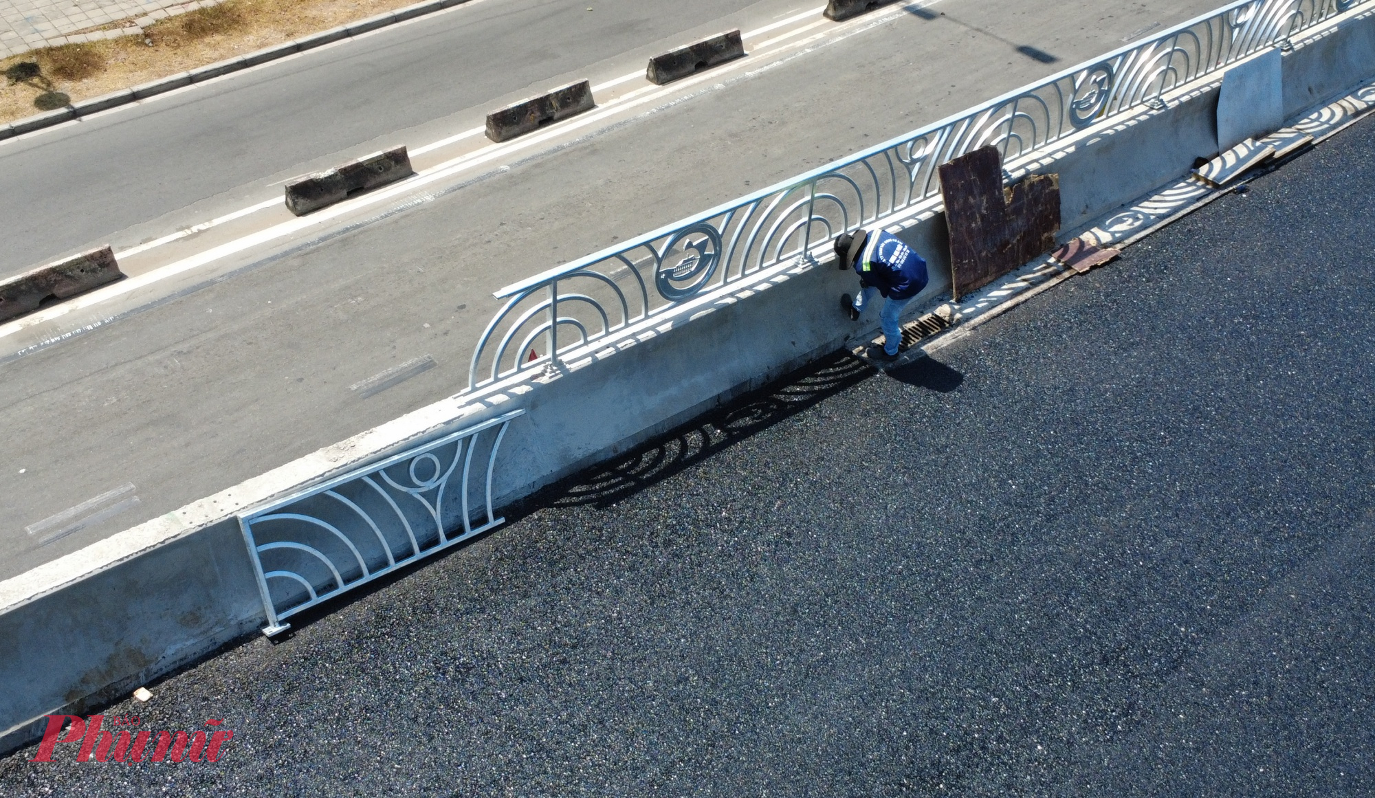 Các công nhân đang lắp đặt một đoạn lan can trên giữa cầu.