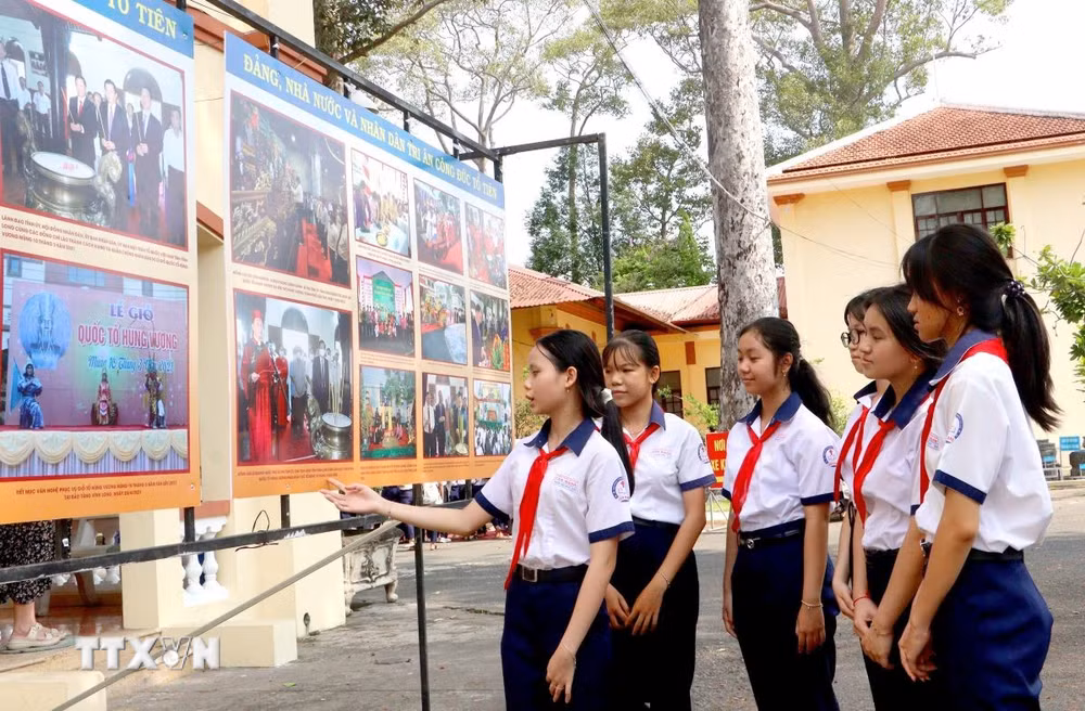 Học sinh tham quan trưng bày hình ảnh về hoạt động Giỗ Tổ Hùng Vương tại tỉnh Vĩnh Long qua các thời kỳ. (Ảnh: Lê Thúy Hằng/TTXVN)