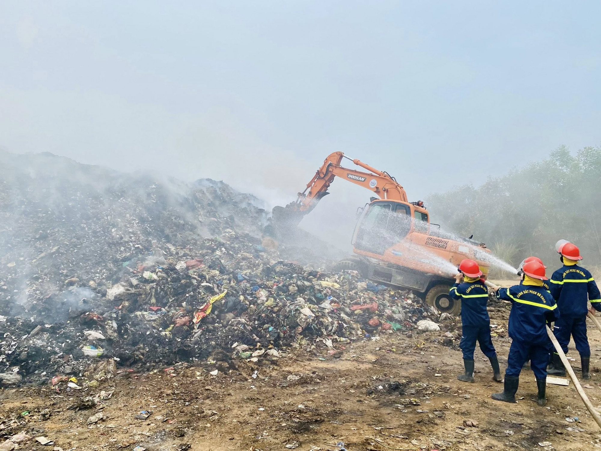 Nhiều máy múc được huy động tới hiện trường khơi rác để phun nước dập lửa - Ảnh: Khánh Trung