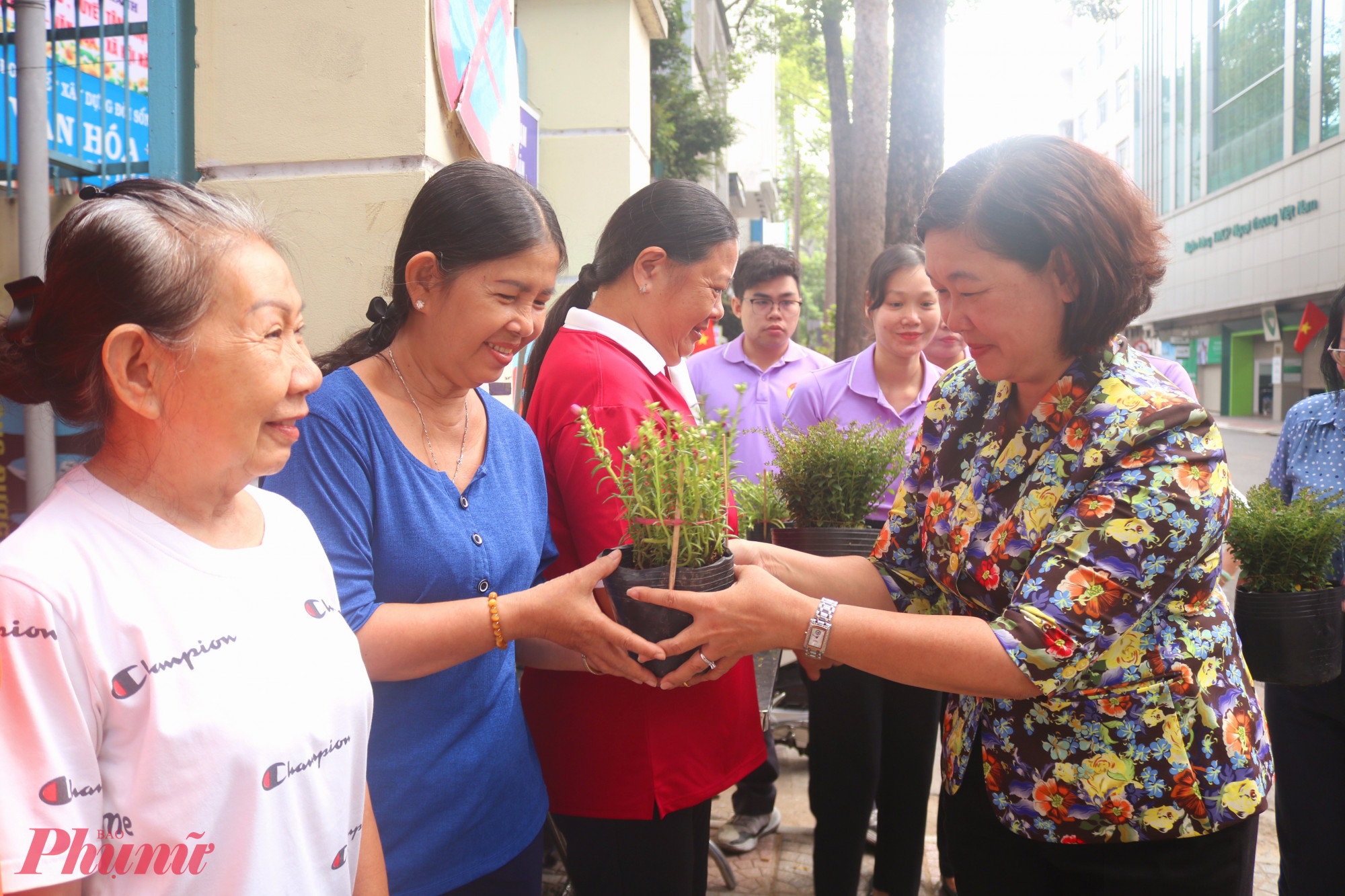 Tại lễ ra mắt công trình, ban tổ chức tặng chậu hoa mười giờ để khuyến khích người dân  2 khu phố 26, 27 cùng trồng, chăm sóc cây, tạo mảng xanh cho gia đình và khu phố. Trong ảnh là bà Hoàng Thị Tố Nga - Bí thư Đảng ủy, Chủ tịch HĐND phường Bến Thành – trao chậu hoa đến đại diện các hộ dân - Ảnh: Thảo Nguyên