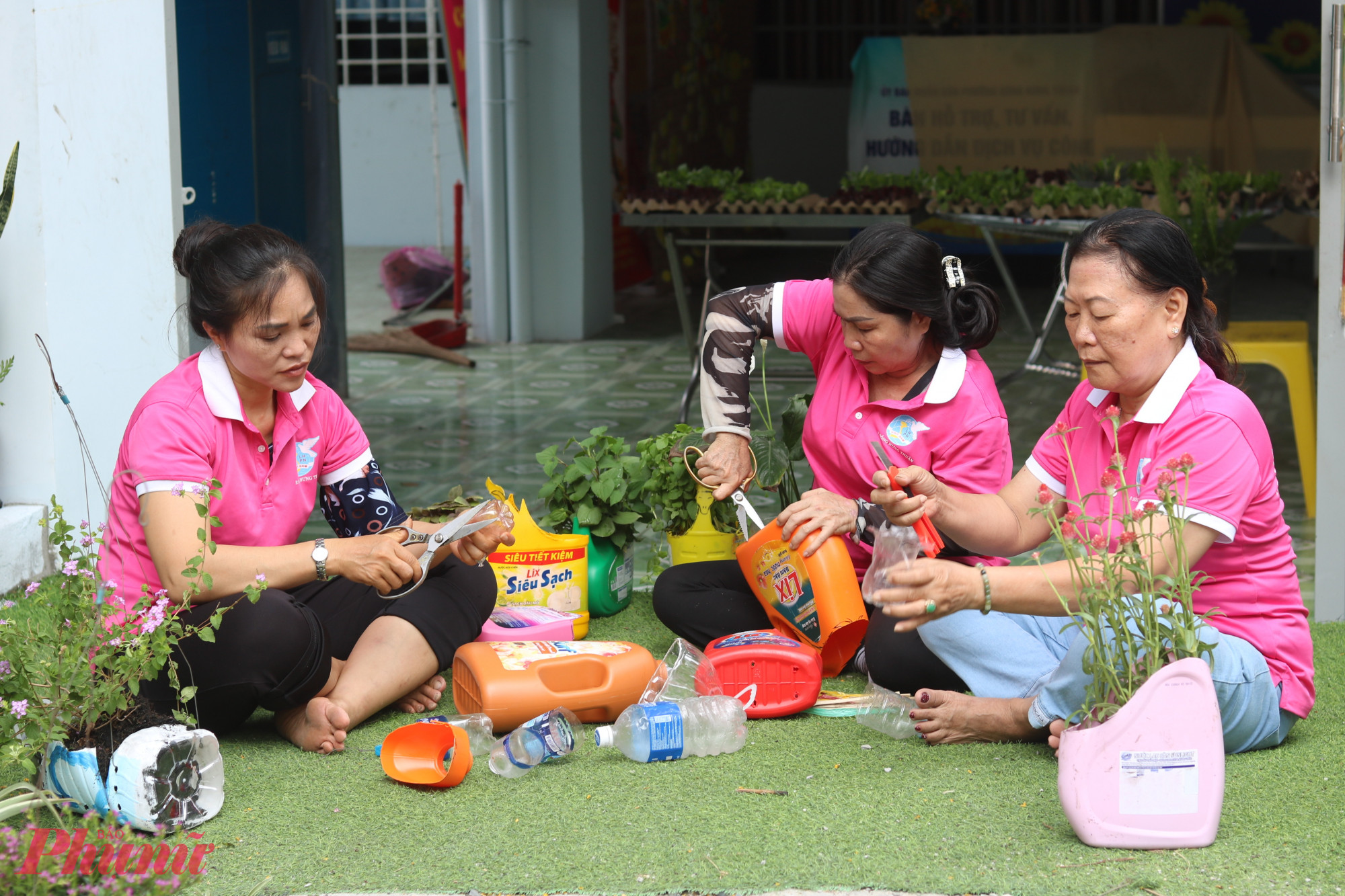 Từ đầu năm 2026 đến nay, cán bộ, hội viên phụ nữ khu phố 46, phường Đông Hưng Thuận, TPHCM đã cùng nhau cắt, gọt tạo hình những bình nước 5 lít, ly nhựa, các bình đựng nước giặt và nước rửa chén cũ thành chậu trồng hoa. Những người có đôi tay khỏe và khéo như các dì, chị Lê Thị Điệp, Nguyễn Thị Kim Yến, Trần Thị Anh Đào (từ phải qua) phụ trách việc cắt, gọt chai, bình nhựa tạo hình chậu. Chị Kim Yến có quầy bán nước ép tại nhà. Chi hội đã dùng bã trái cây sau khi ép (thơm, dưa hấu, cà rốt, ổi…) từ quầy nước nhà chị Yến để ủ với men vi sinh tạo thành nước tưới cho cây.