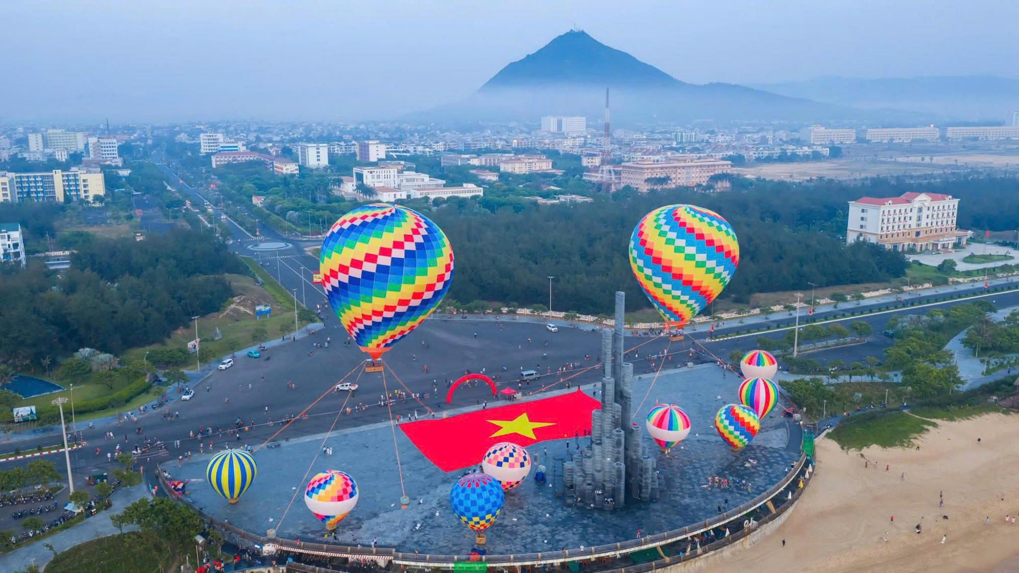 Quảng trường Tháp Nghinh Phong nhìn từ biển vào nổi bật với khinh khí cầu sắc màu, xa xa là núi Chóp Chài. Ảnh: Nghinh Phong Media