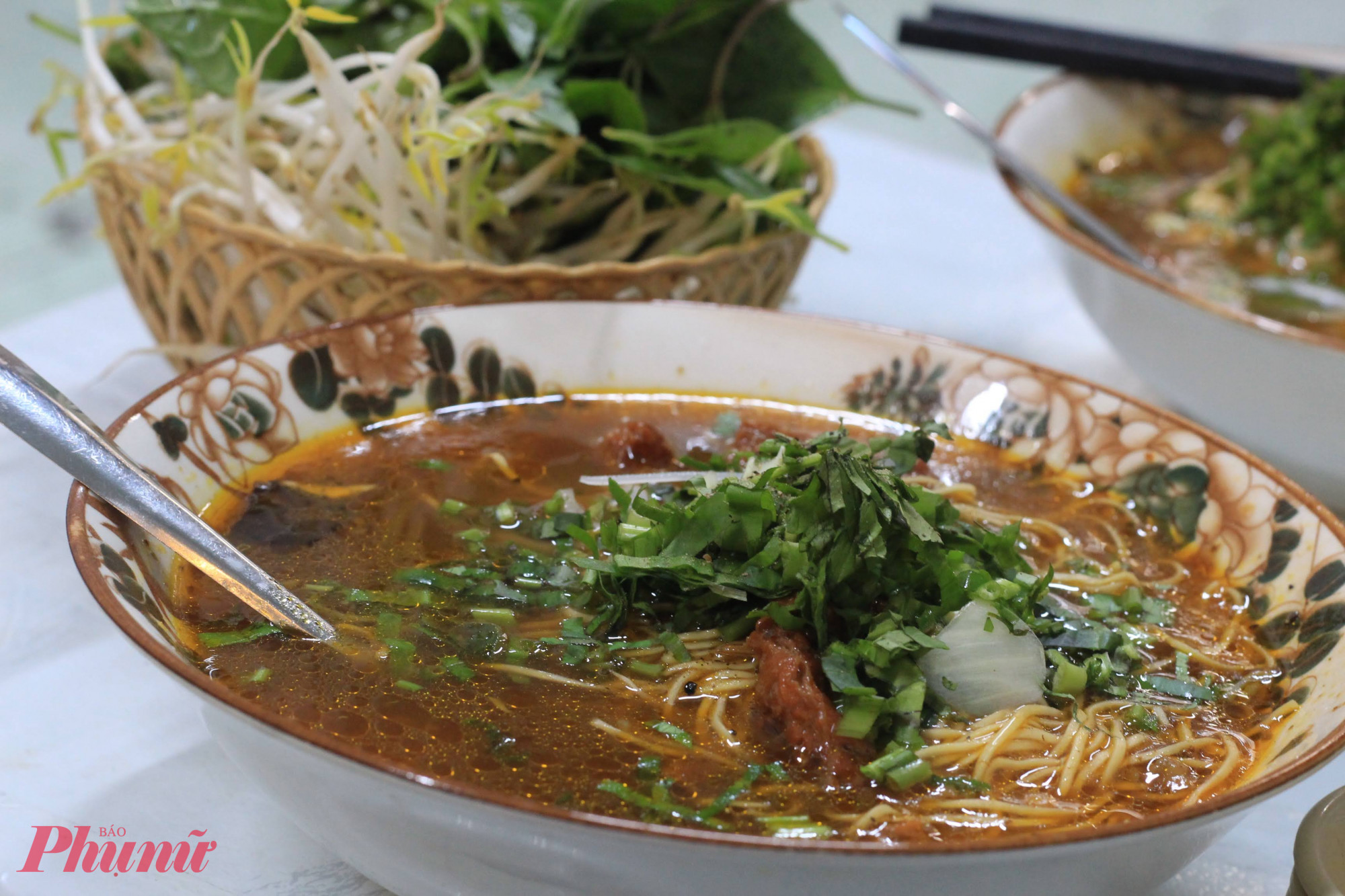 Những buổi chiều mưa se lạnh, một tô mì hoặc hủ tiếu bò kho nghi ngút khói luôn đủ sức kéo người ta ghé lại. Phần nước dùng đỏ au, thơm mùi quế hồi và sả, sánh nhẹ nhưng không ngấy. Những miếng bò hầm mềm, gân dai vừa tới, cà rốt ngọt bùi, ăn cùng sợi mì trứng vàng óng hoặc hủ tiếu dai mềm đều hợp. Chỉ cần thêm chút sa tế, vắt miếng chanh, húp muỗng nước nóng là thấy vị cay ấm lan dần. Đây là kiểu món ăn trời càng mưa, càng khiến chiếc bụng thấy thèm một cách rất khó cưỡng.