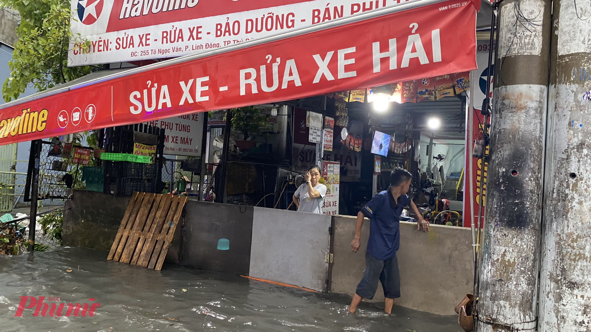 Người dân trên đường Tô Ngọc Vân dùng miếng ván cao hơn 1m để chắn nước tràn vào nhà, mọi hoạt động buôn bán phải dừng lại để canh sóng nước