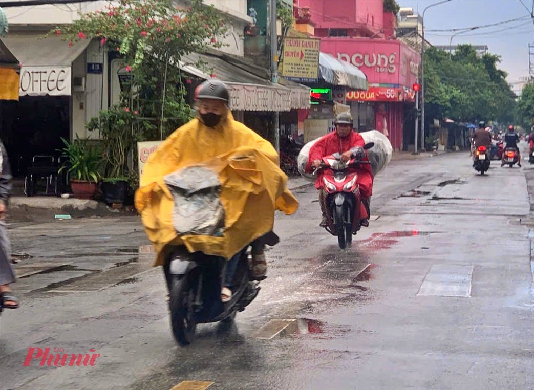 Người dân mặc áo mưa đi đường ở khu vực quận Tân Phú cũ - Ảnh: Danh Xuân