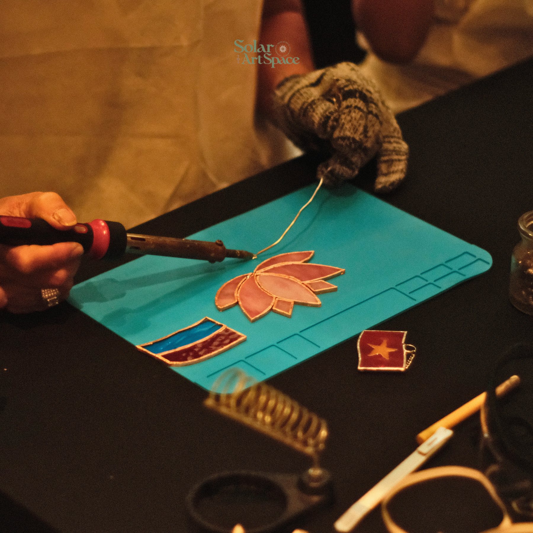 Solar Art Space (98 Tôn Thất Tùng, phường Bến Thành) được nhiều bạn trẻ biết đến qua các workshop tranh kính màu và vẽ thủy tinh. Giữa nhịp sống vội vã của trung tâm thành phố, nơi đây như một khoảng lặng dịu dàng, để người ta tạm rời màn hình điện thoại, ngồi xuống bên ô cửa ngập nắng và kiên nhẫn với từng đường nét nhỏ. Không gian ấm áp, đủ riêng tư để mỗi người tập trung vào tác phẩm của mình.  Với những ai yêu sự tỉ mỉ và cẩn thận, việc chọn màu, đi viền, chờ lớp sơn khô hay ghép từng mảng kính trở thành một trải nghiệm vừa thư giãn vừa đầy hứng khởi. Mỗi sản phẩm hoàn thiện không chỉ là món đồ trang trí mà còn là kỷ vật lưu giữ cảm xúc của một buổi chiều sống chậm, nơi ánh sáng và màu sắc ở lại theo cách rực rỡ rất riêng.