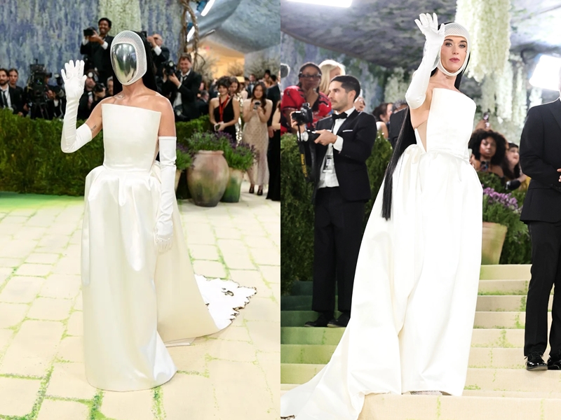 Tại thảm đỏ Met Gala 2026, Katy Perry gây bất ngờ với phong cách thời trang mang hơi hướng vị lai đầy ấn tượng, gợi liên tưởng đến hình ảnh một phi hành gia. Nữ ca sĩ diện một chiếc đầm quây dáng phồng (ball gown) cực đại với chất liệu vải lụa bóng cao cấp. Thân váy được cắt may tối giản nhưng có độ xòe rộng và phần đuôi dài thướt tha. Chi tiết đắt giá nhất chính là chiếc mũ trùm đầu bằng lưới màu trắng, ôm sát lấy khuôn mặt và phần cổ, mô phỏng hình ảnh chiếc mũ bảo hộ của các phi hành gia một cách đầy nghệ thuật.