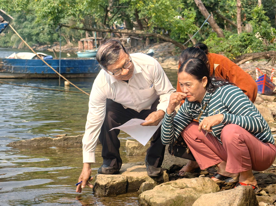 Chị Trần Thị Lan (bìa phải) - ở thôn Thạch Bồ, xã Hòa Vang - kiểm tra mùi nước sông Cu Đê ở hạ nguồn - ẢNH: U.N.