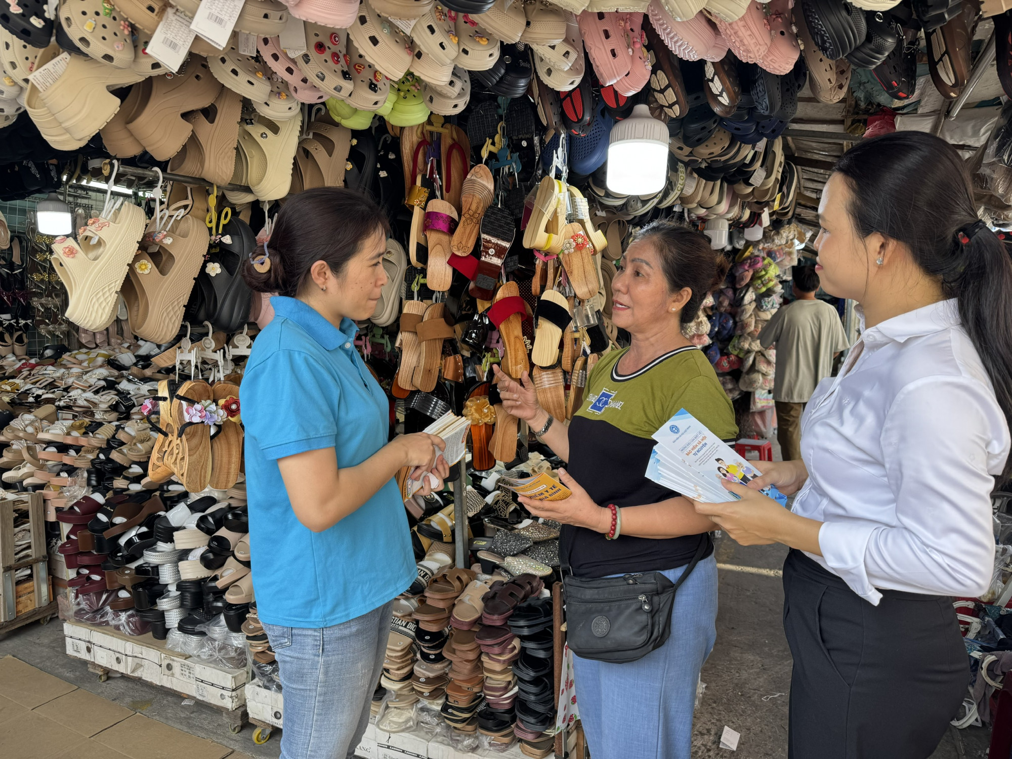 Nhân viên BHXH và Công ty Bảo hiểm PVI đang tư vấn cho tiểu thương tại chợ Tân Mỹ - Ảnh: BHXH TPHCM