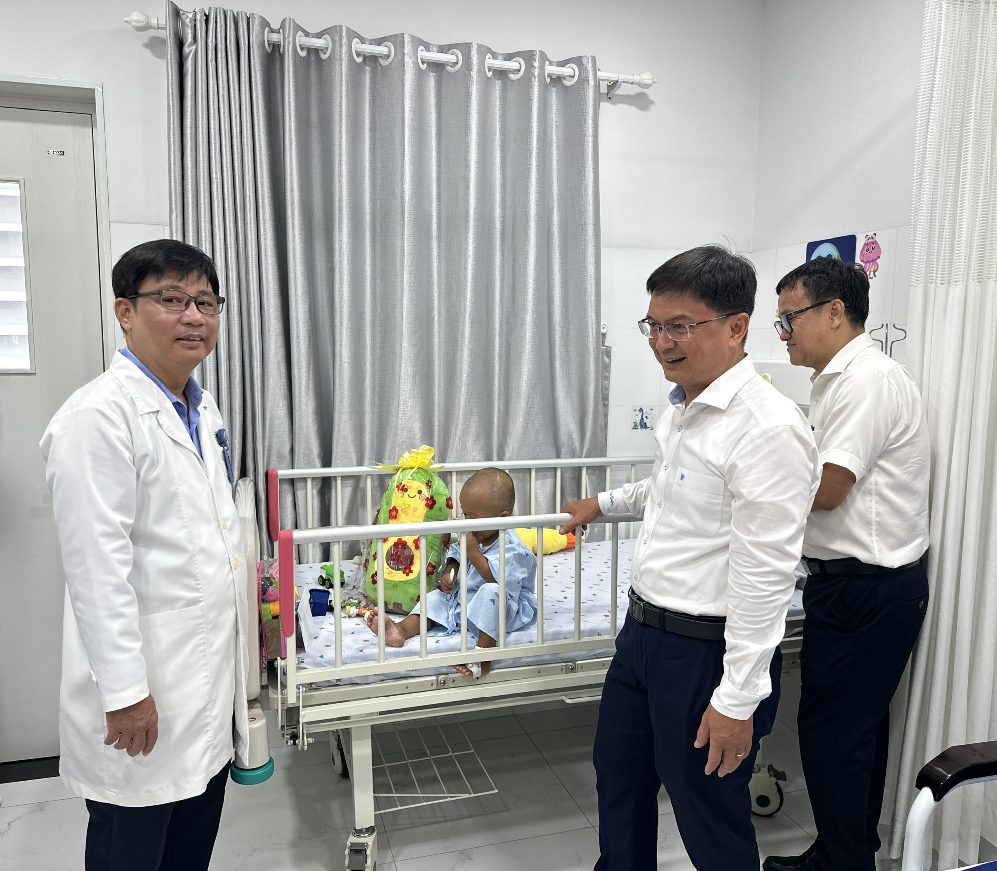 Tiến sĩ, bác sĩ Ngô Ngọc Quang Minh - Giám đốc Bệnh viện Nhi đồng 1 (bìa trái) cùng đoàn công tác thăm sức khỏe bé K., ảnh BVCC