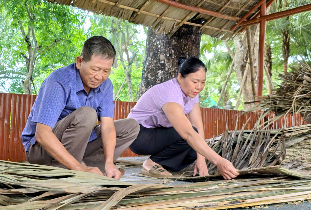 Ông Huệ cùng bà Lam thực hiện đan tranh dựng gian hàng chuẩn bị cho sự kiện ở khu di tích quốc gia đặc biệt Kim Liên