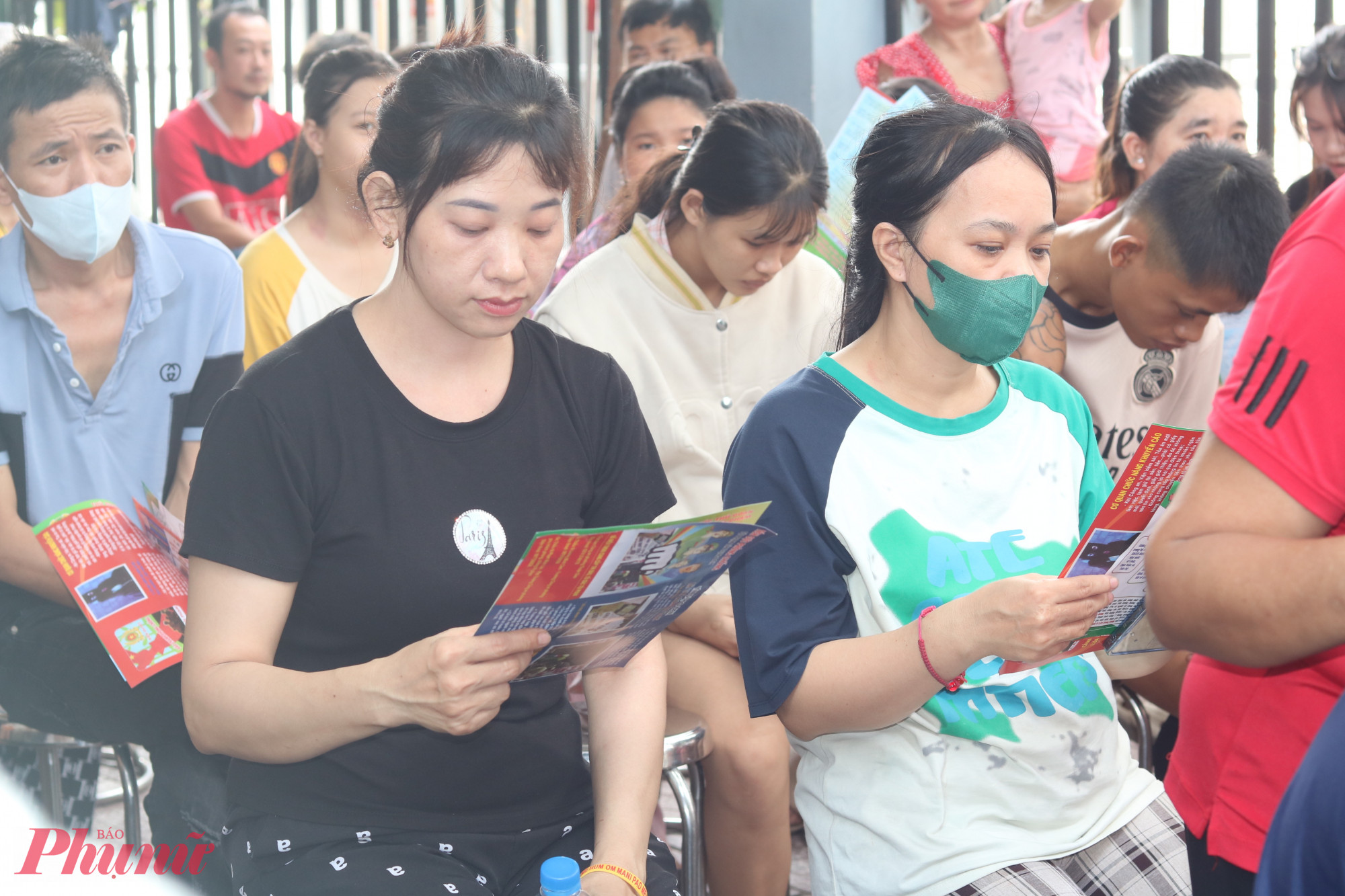 Các chị em dự nghe tuyên truyền và chăm chú đọc tài liệu thông tin các phương thức, thủ đoạn và cách phòng ngừa tội phạm lừa đảo chiếm đoạt tài sản qua mạng xã hội - Ảnh: Mẫn Nhi