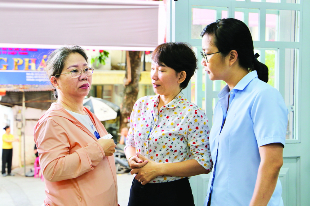 Cán bộ Trung tâm Phục vụ hành chính công phường Tân Sơn Nhất (đứng bên phải) hướng dẫn, hỗ trợ người dân làm thủ tục