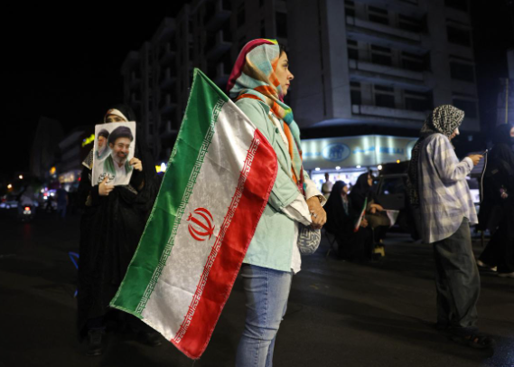  Phụ nữ cầm quốc kỳ Iran và ảnh của nhà lãnh đạo tối cao Mojtaba Khamenei cùng người tiền nhiệm và người cha quá cố Ali Khamenei tại quảng trường Hafte Tir ở Tehran, ngày 17 tháng 5 năm 2026. (Ảnh AFP)