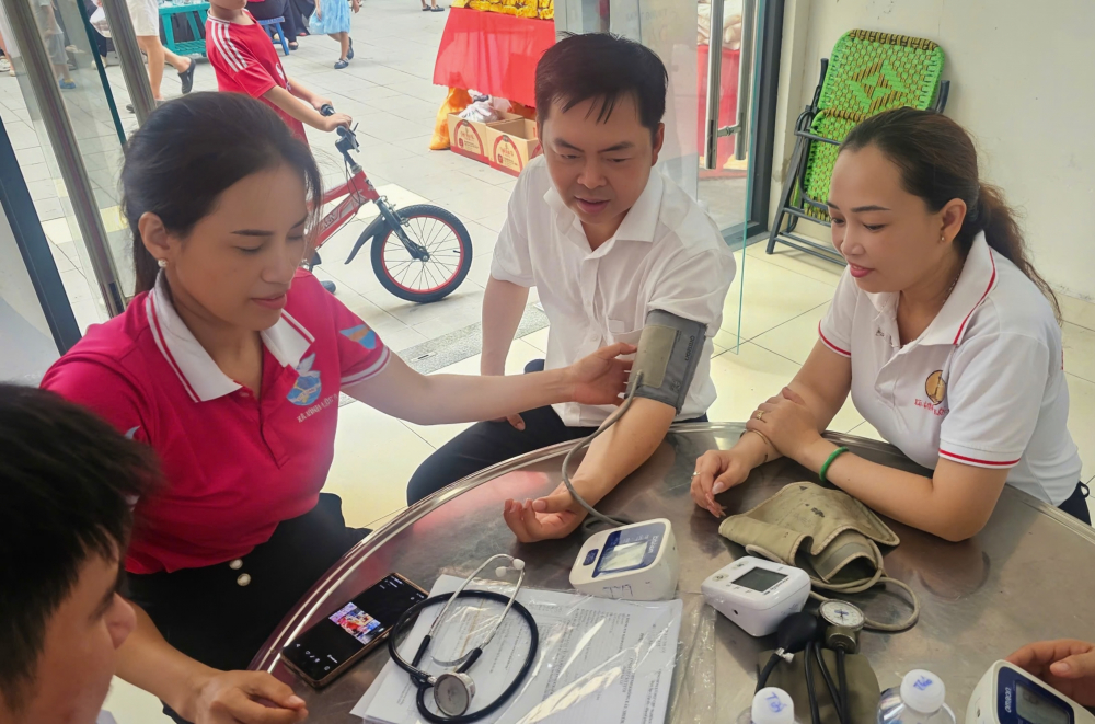 Hội viên phụ nữ hỗ trợ đo huyết áp. Ảnh: NH