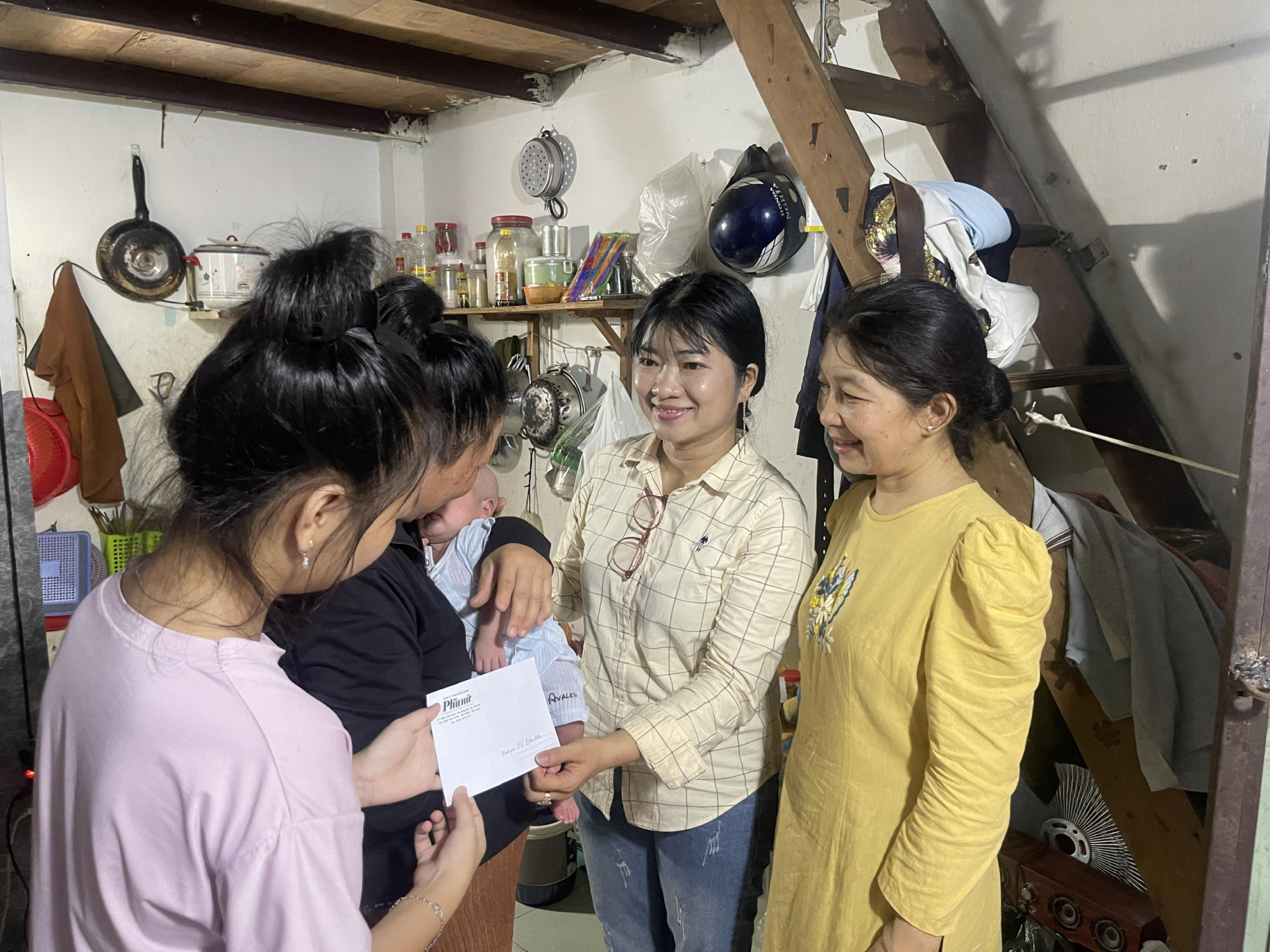 Chị Nguyễn Thị Thanh Thúy (bìa phải) cùng đại diện Báo Phụ nữ TPHCM đến thăm và số tiền bạn đọc giúp đỡ bé D.B.N. - Ãnh: Trần Trúc