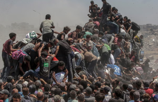 Người dân Palestine tị nạn chen chúc giành những bao bột mì từ một xe tải chở hàng viện trợ gần điểm phân phối thực phẩm ở phía bắc Dải Gaza vào tháng 7 năm 2025. Ảnh: Mohammed Saber/EPA