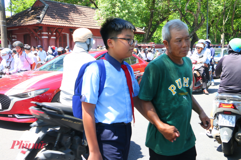 Ông dắt cháu đi nhanh ra khởi trường thi về nhà tránh nắng