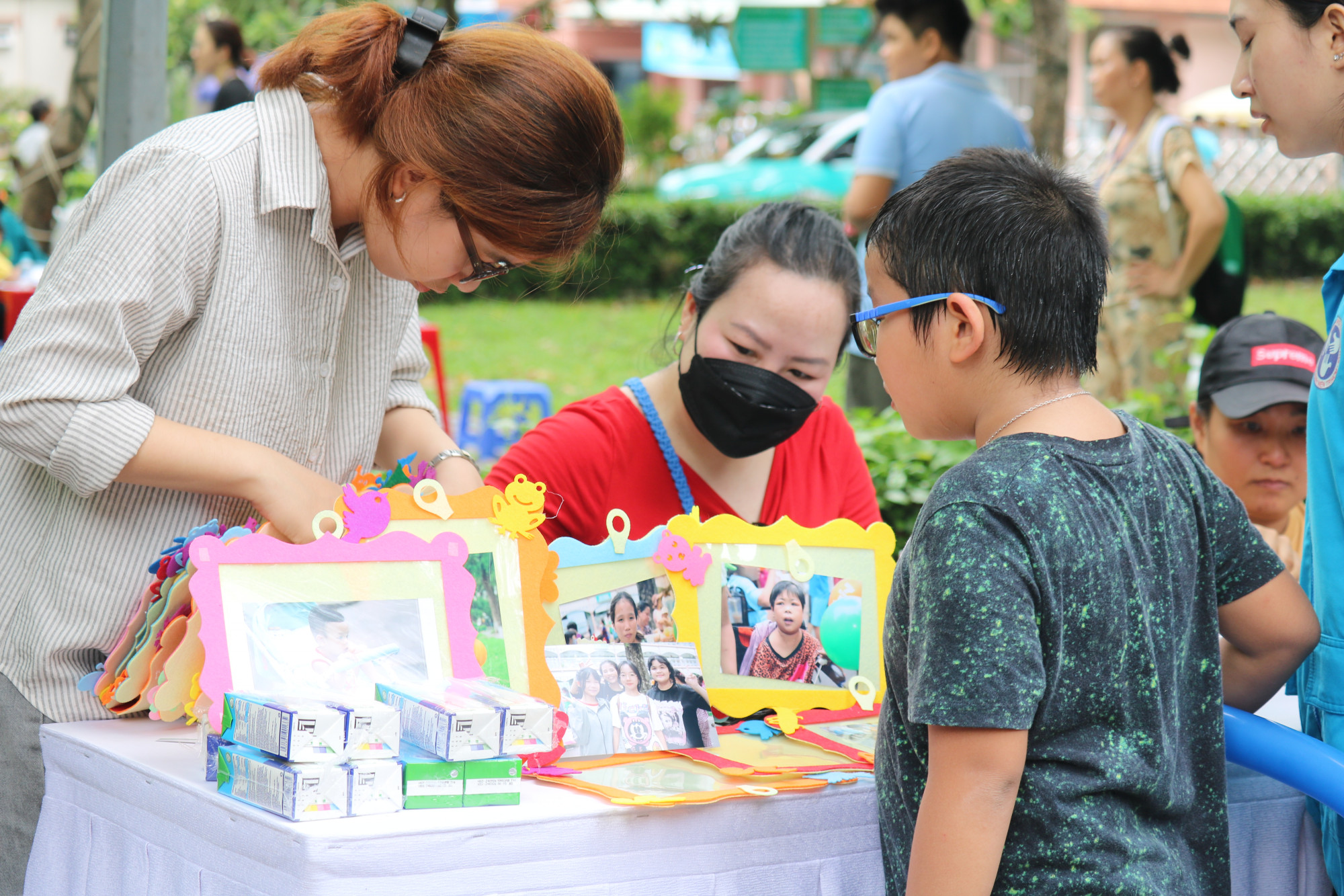 Bé trai vừa tham gia đổi quà kiếm được từ trò chơi dân gian và tìm ảnh chụp của mình
