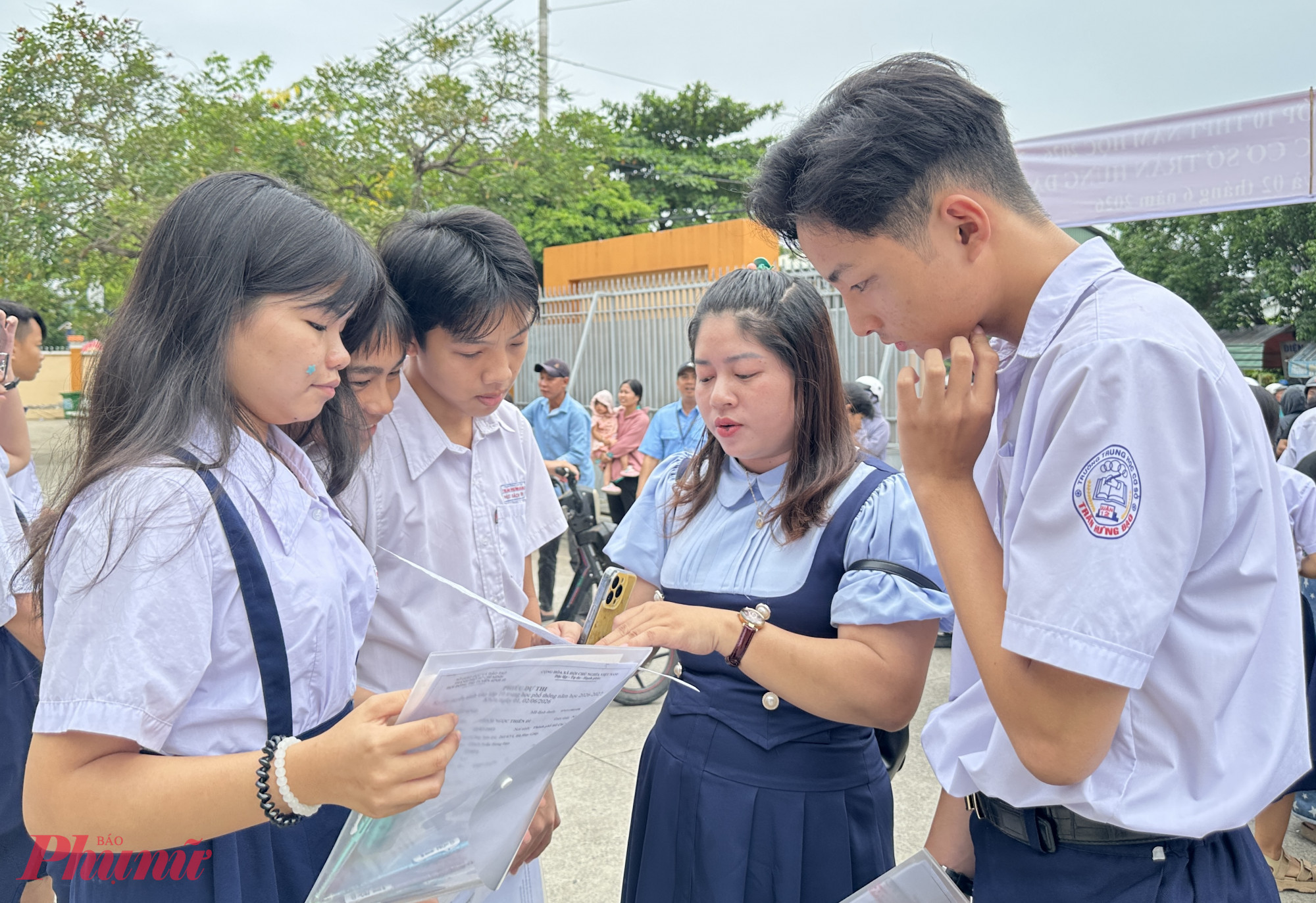 Thí sinh trao đổi đề thi với giáo viên của mình tại điểm thi Trường THCS Trần Hưng Đạo - Ảnh: Nguyễn Loan