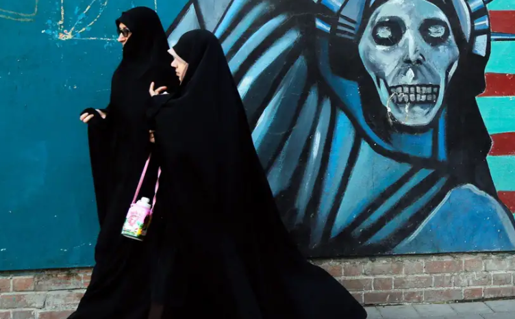Những người phụ nữ Iran đi ngang qua một bức tranh tường chống Mỹ trên đường đến đại sứ quán Mỹ cũ ở Tehran.Ảnh: A