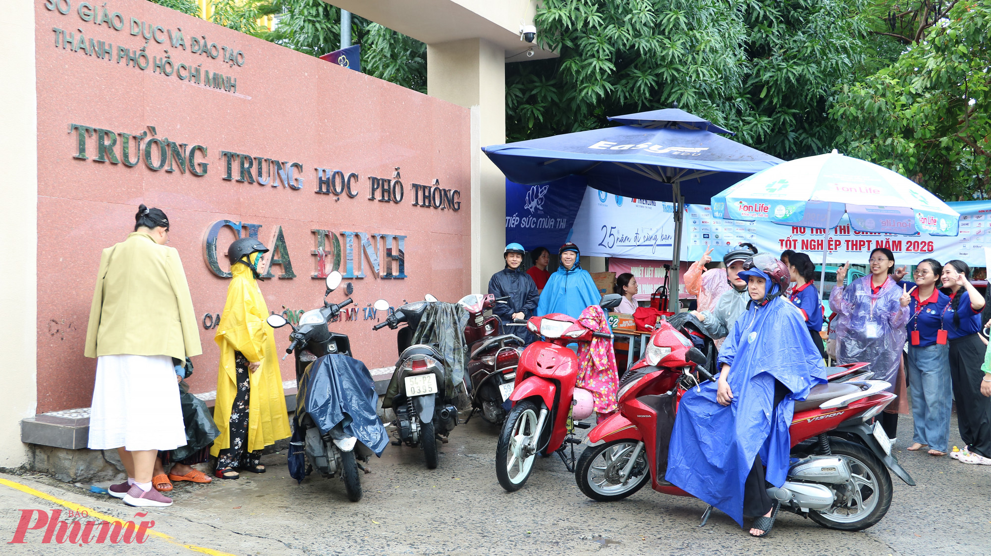 Phụ huynh dầm mưa đợi con trước cổng trường - Ảnh: Trang Thư