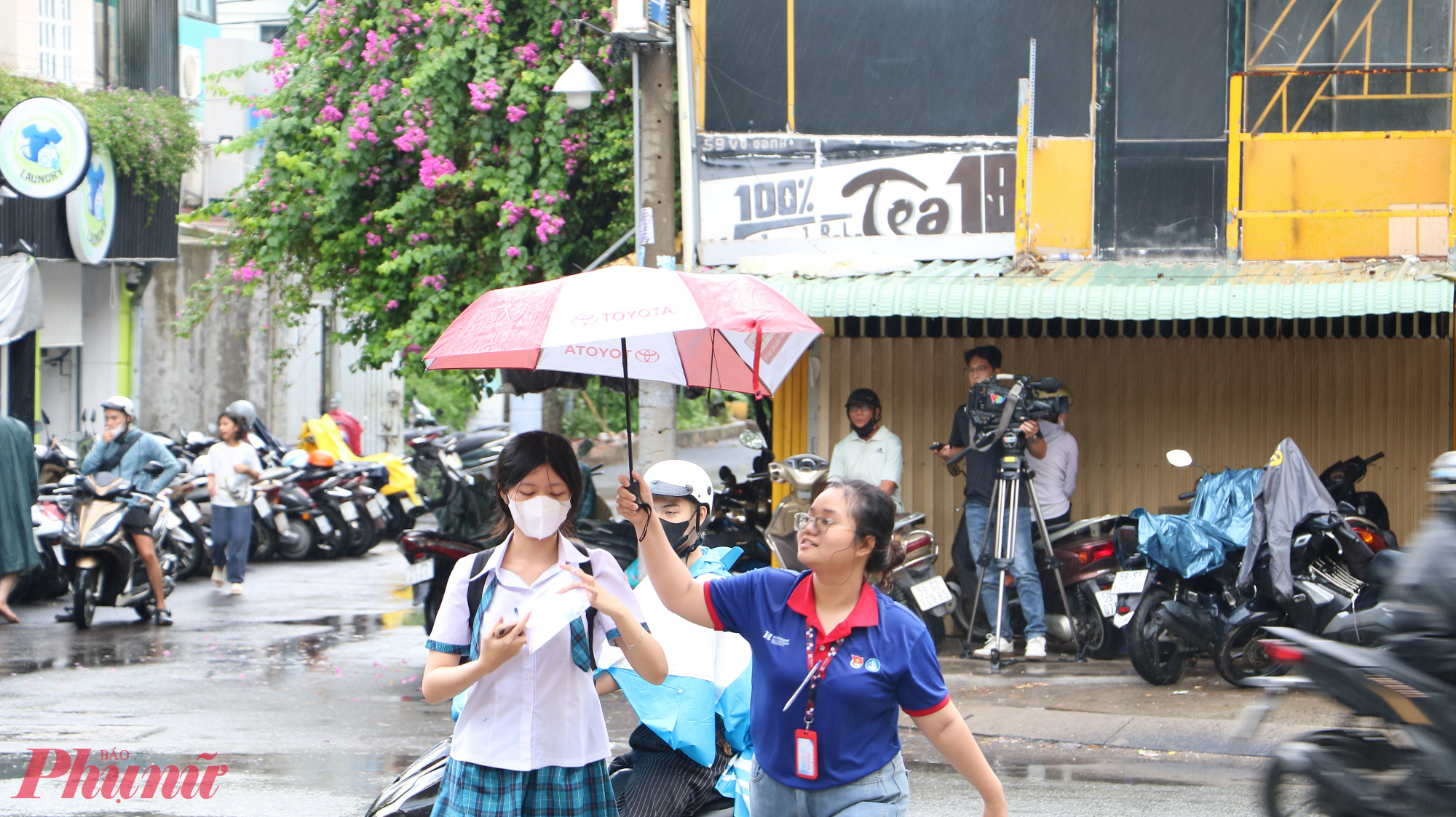 Sinh viên tình nguyện hỗ trợ thí sinh vào điểm thi Trường THPT Gia Đình sau cơn mưa lớn - Ảnh: Trang Thư