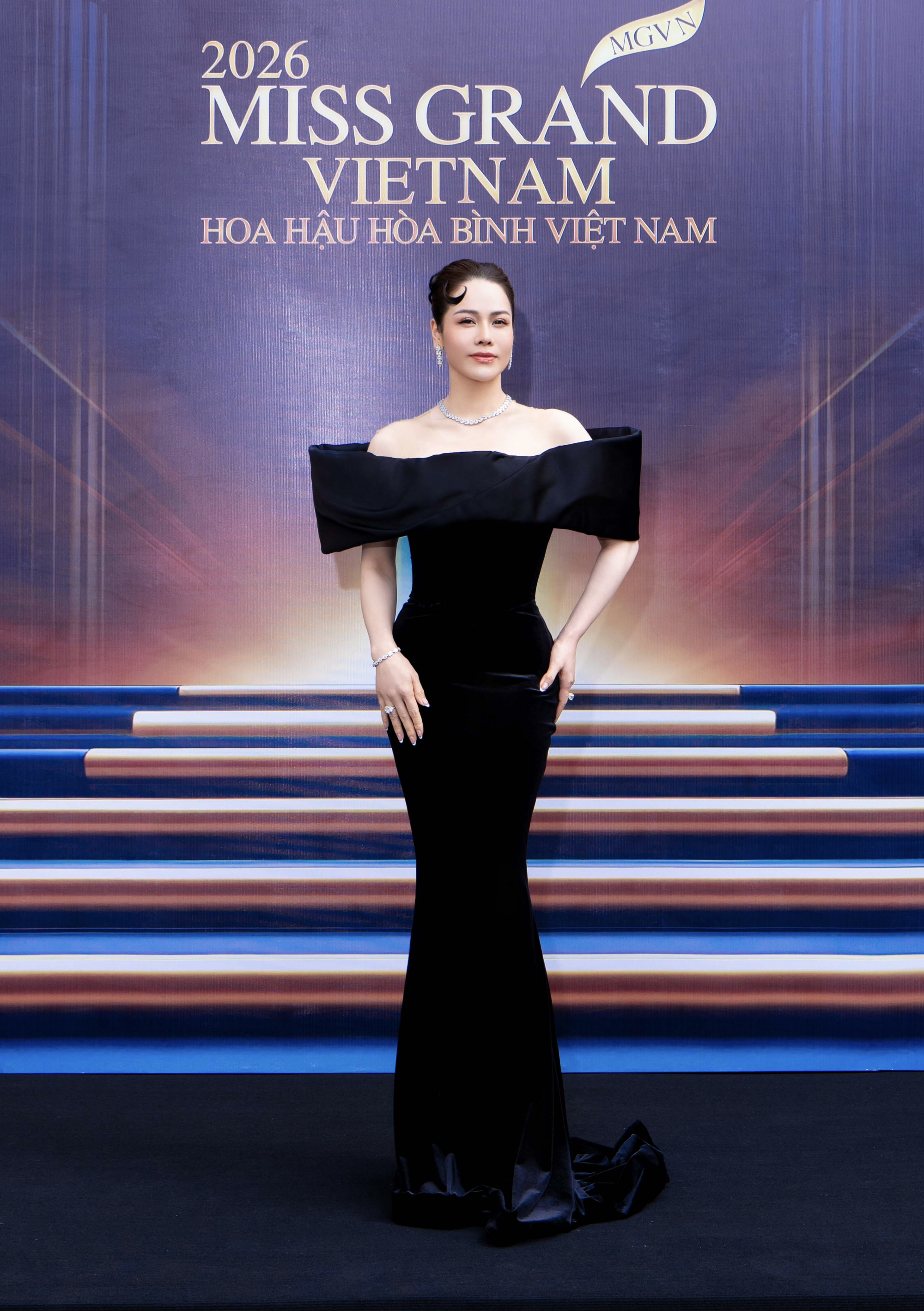Chiều 17/6, BTC cuộc thi Miss Grand Việt Nam 2026 - Hoa hậu Hoà bình Việt Nam 2026 tổ chức họp báo công bố mùa giải năm nay.   Diễn viên Nhật Kim Anh là một trong những giám khảo của cuộc thi năm nay. Cô diện đầm trễ vai ôm sát phối trang sức kim cương. Bà mẹ hai con sở hữu vóc dáng gợi cảm không kém các hoa hậu, á hậu. 