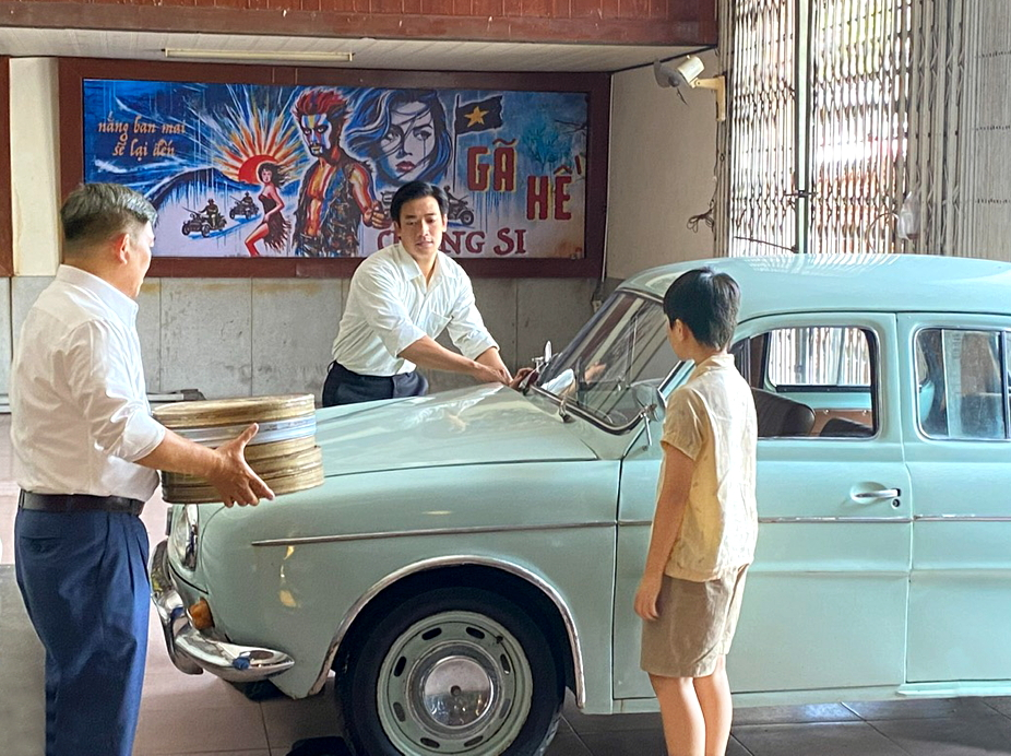 Một cảnh trong phim Chớp bóng xuất hiện 2 đạo cụ xưa là hộp phim và chiếc xe cổ - ẢNH: HMH