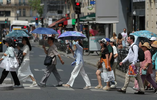 Du khách ở Paris che ô để tránh nắng vào thứ Ba. Ảnh: Thomas Samson/AFP/Getty Images