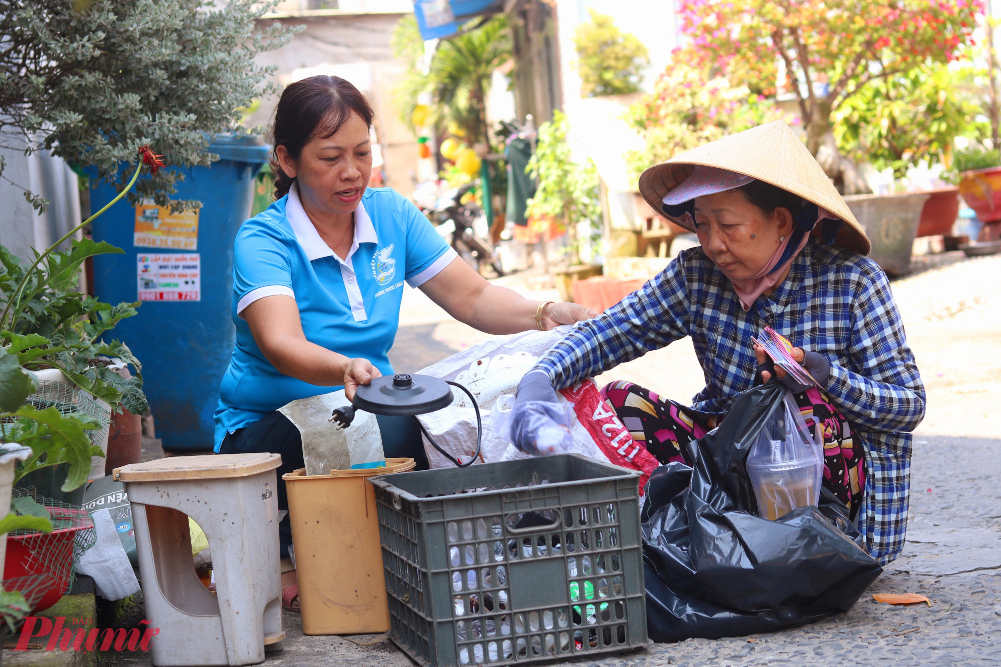 Chị Thương (bìa trái) thu gom rác thải tái chế trong khu nhà trọ để tặng bà Đành - Ảnh: Thảo Nguyên