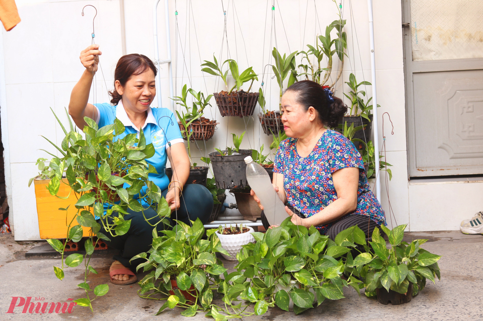 Chị Thương (bìa trái) khuyến khích và thường xuyên hỗ trợ bà Xuân chăm sóc mảng xanh trong khu nhà trọ - Ảnh: Thảo Nguyên