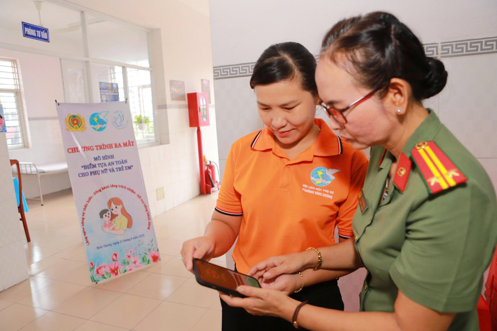 Các chị em nhận tờ rơi tuyên truyền và được hướng dẫn cài đặt ứng dụng SOS An ninh trật tự - Công an TPHCM - Ảnh: Hội LHPN phường Bình Dương