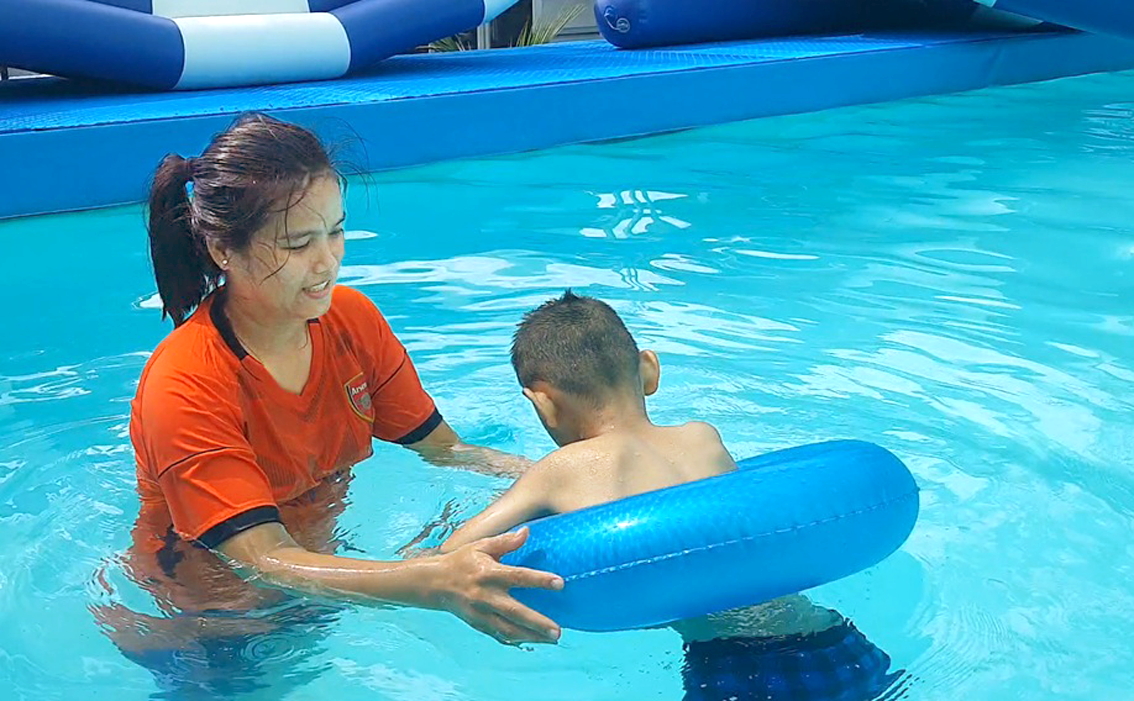 Phụ huynh đang tập bơi cho con dịp hè